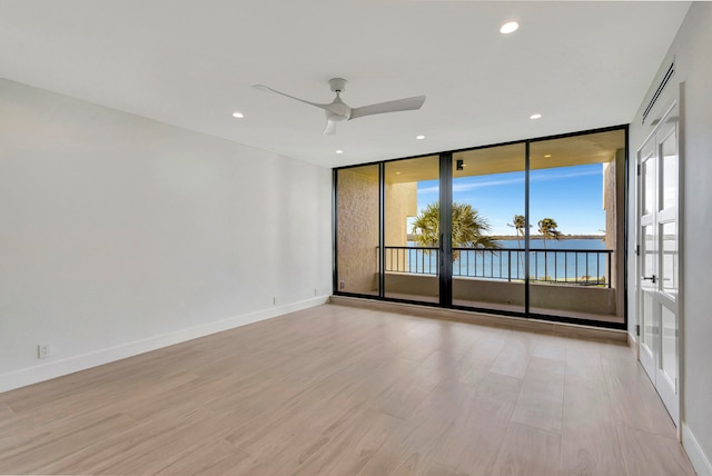 unfurnished room with light hardwood / wood-style flooring, ceiling fan, and floor to ceiling windows