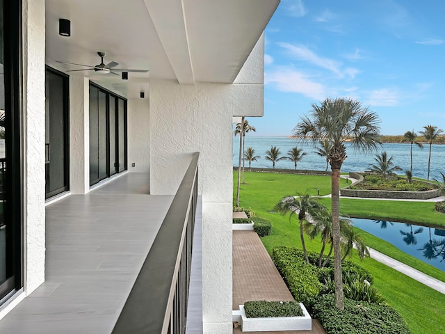 balcony with ceiling fan and a water view