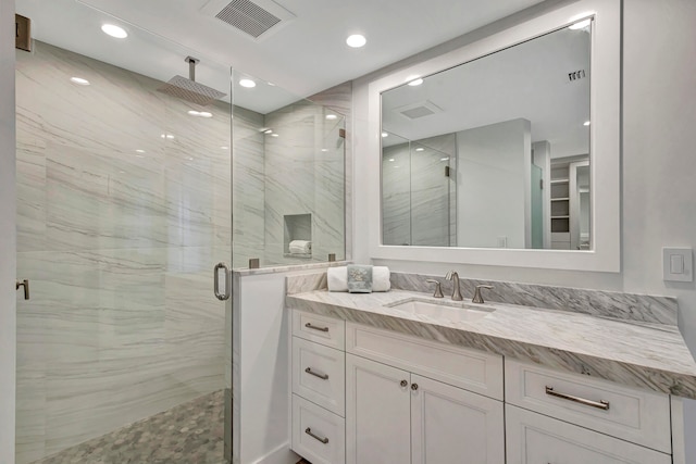 bathroom featuring a shower with shower door and vanity