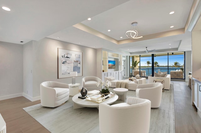 living room featuring a tray ceiling, light hardwood / wood-style flooring, and ceiling fan