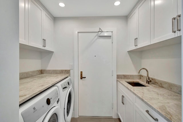 clothes washing area featuring sink, cabinets, and washer and clothes dryer