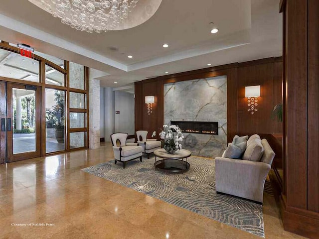 interior space featuring an inviting chandelier, a premium fireplace, tile patterned floors, and a tray ceiling