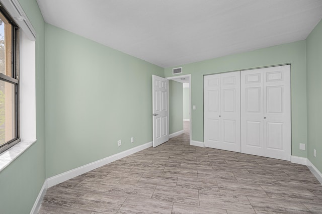 unfurnished bedroom with light tile patterned floors, multiple windows, and a closet