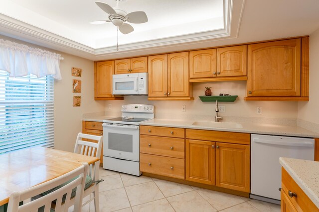 kitchen with sink, a raised ceiling, light tile patterned floors, white appliances, and ceiling fan