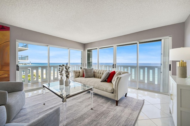 tiled living room featuring a textured ceiling and a water view