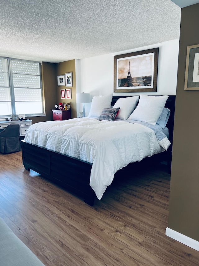 bedroom with a textured ceiling and wood-type flooring