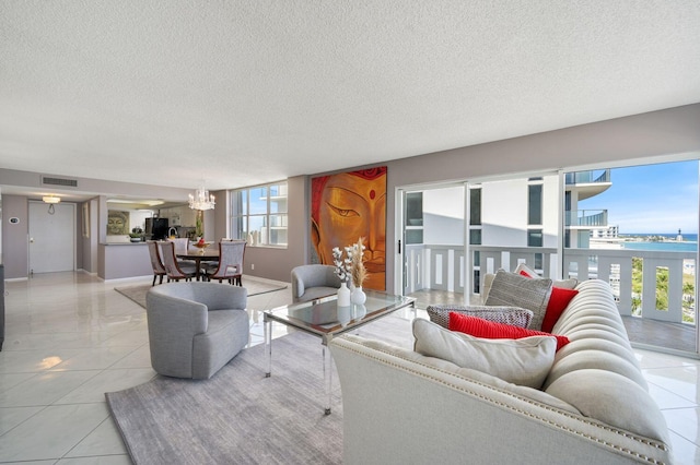 living room with plenty of natural light, a water view, light tile patterned floors, and an inviting chandelier