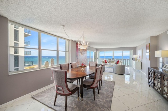 tiled dining space featuring a textured ceiling, a water view, and an inviting chandelier