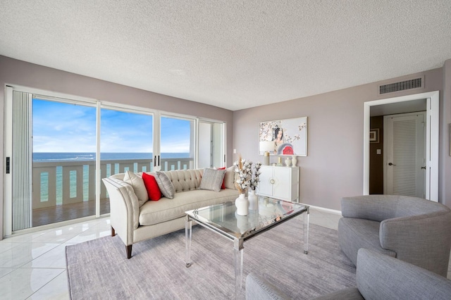 tiled living room featuring a textured ceiling and a water view