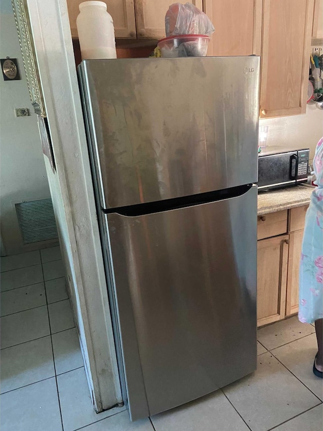 kitchen featuring light brown cabinetry, light tile patterned floors, and stainless steel fridge