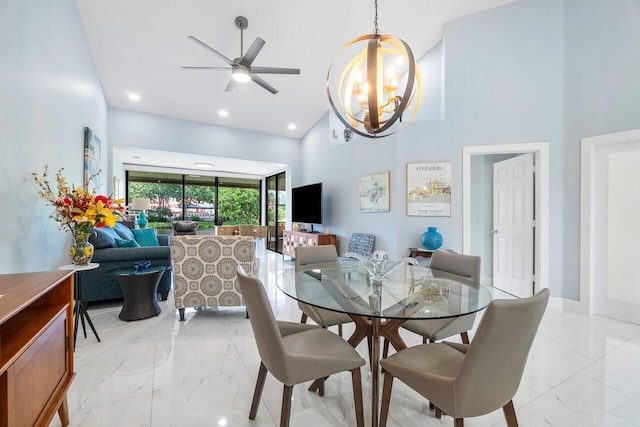 tiled dining room with ceiling fan with notable chandelier and a towering ceiling