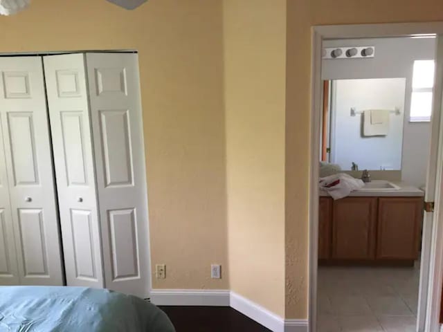 bedroom with sink, tile patterned floors, and a closet