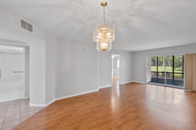 empty room featuring an inviting chandelier and light hardwood / wood-style floors