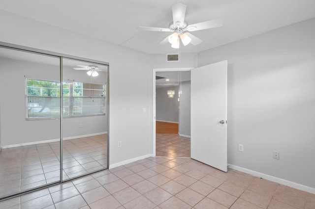 unfurnished bedroom with ceiling fan, light tile patterned floors, and a closet