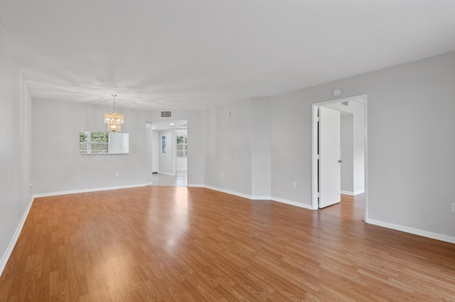 spare room with light wood-type flooring and a chandelier