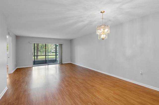 spare room featuring a notable chandelier and hardwood / wood-style floors