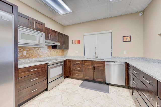 kitchen featuring kitchen peninsula, light stone counters, stainless steel appliances, sink, and light tile patterned flooring