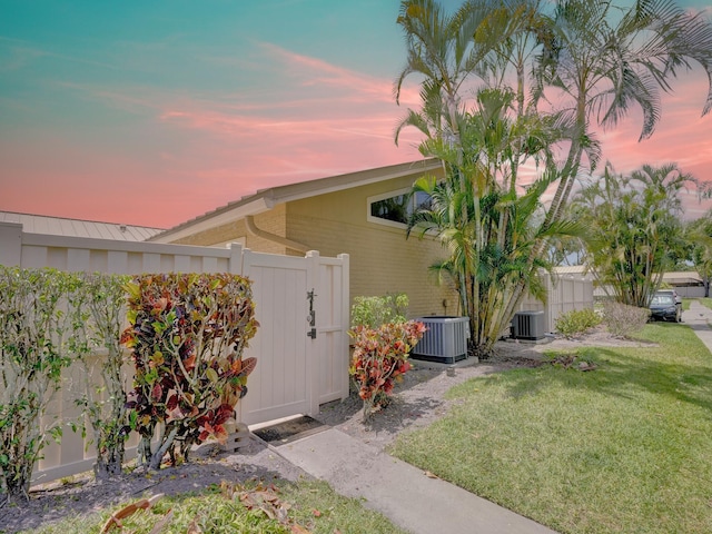 property exterior at dusk with a yard and cooling unit