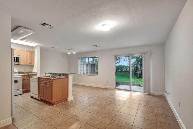 kitchen with a center island, a textured ceiling, light tile patterned floors, white appliances, and light stone countertops