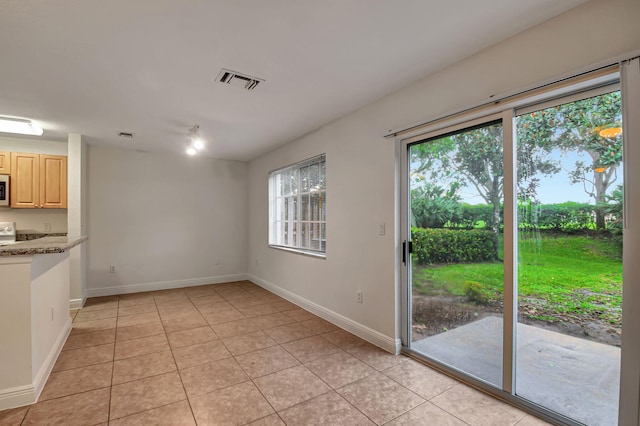 unfurnished dining area with light tile patterned flooring