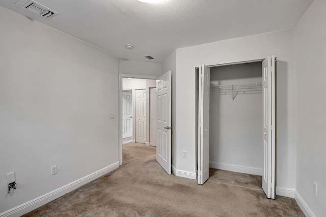 unfurnished bedroom featuring light carpet and a closet