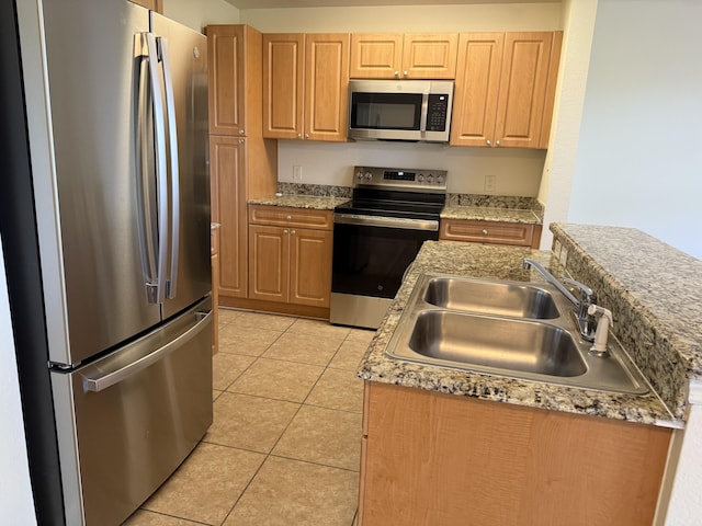 kitchen with stainless steel appliances, an island with sink, sink, and light tile patterned floors