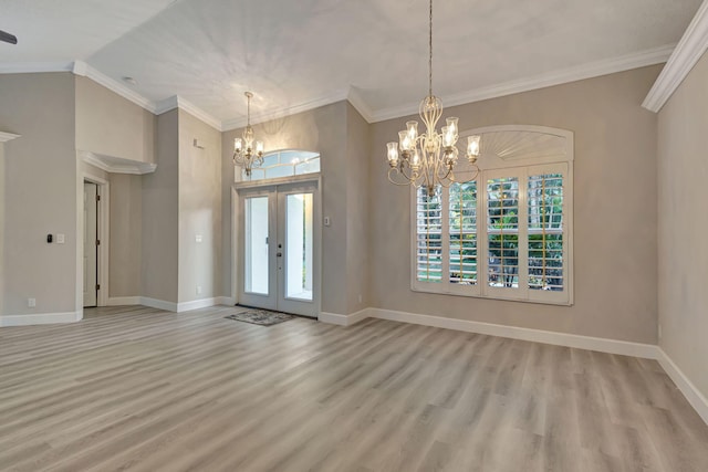 unfurnished living room with ceiling fan with notable chandelier, light hardwood / wood-style floors, crown molding, and vaulted ceiling