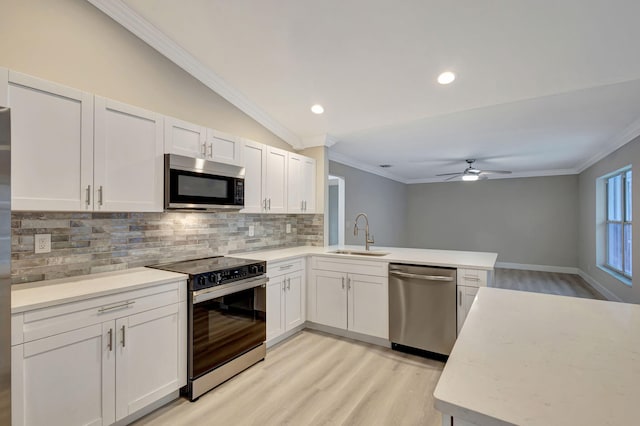 kitchen with sink, white cabinets, stainless steel appliances, and vaulted ceiling