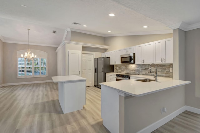 kitchen with kitchen peninsula, appliances with stainless steel finishes, decorative light fixtures, and sink