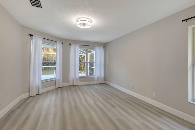 unfurnished room featuring a textured ceiling and light hardwood / wood-style floors