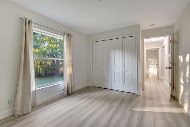 unfurnished bedroom featuring a closet, light hardwood / wood-style flooring, and multiple windows