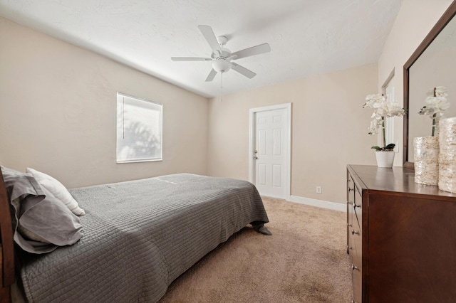 bedroom featuring a textured ceiling, light colored carpet, and ceiling fan