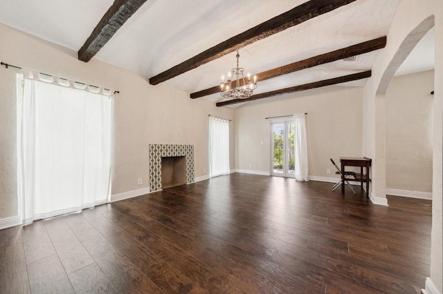 unfurnished living room featuring beam ceiling, a tiled fireplace, an inviting chandelier, and dark hardwood / wood-style flooring