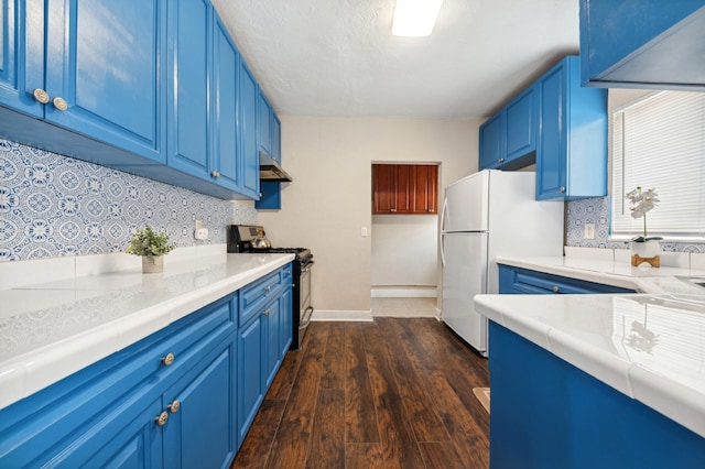 kitchen featuring decorative backsplash, dark hardwood / wood-style flooring, stainless steel stove, blue cabinetry, and white refrigerator