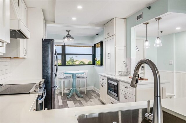 kitchen featuring appliances with stainless steel finishes, light hardwood / wood-style flooring, decorative backsplash, and white cabinetry