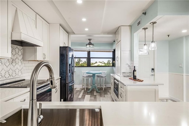 kitchen with custom exhaust hood, decorative backsplash, light hardwood / wood-style floors, refrigerator, and white cabinets