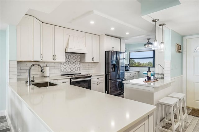 kitchen with appliances with stainless steel finishes, premium range hood, light hardwood / wood-style floors, decorative light fixtures, and sink