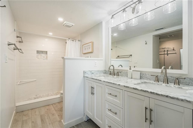 bathroom featuring a shower with shower curtain, wood-type flooring, double vanity, and toilet