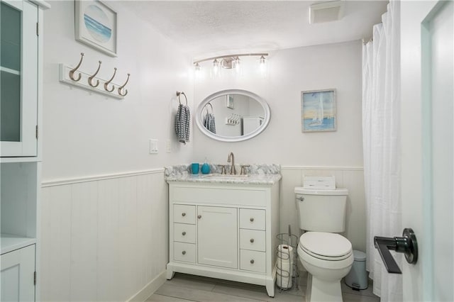 bathroom featuring a textured ceiling, vanity, and toilet