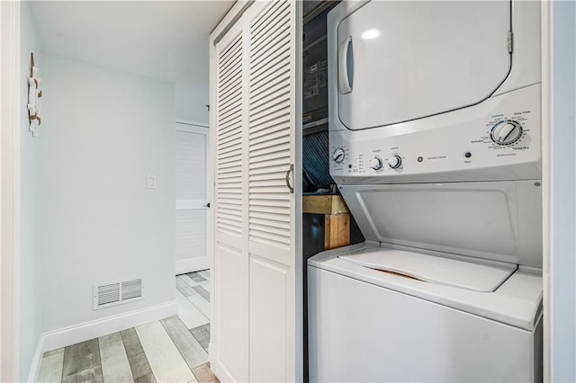 washroom featuring light hardwood / wood-style floors and stacked washer and clothes dryer