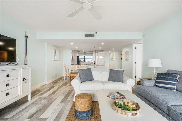 living room with ceiling fan and light hardwood / wood-style flooring