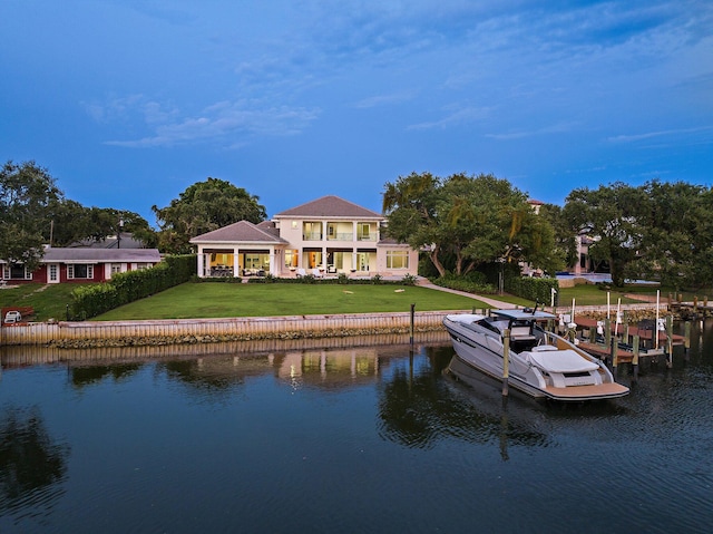 back of house featuring a water view, a balcony, and a lawn