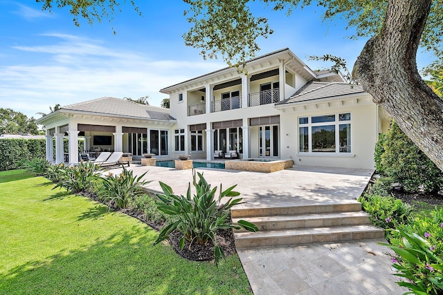 rear view of house featuring a patio, a lawn, and a balcony