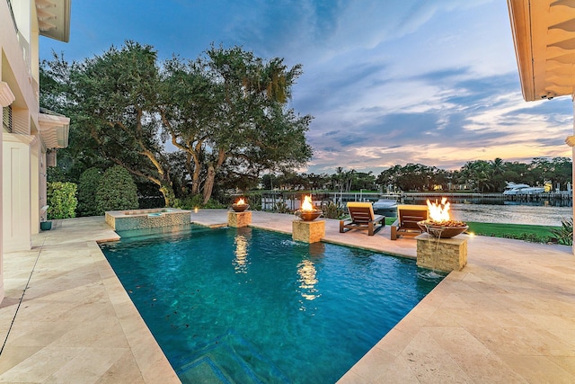 pool at dusk with a patio area and an in ground hot tub