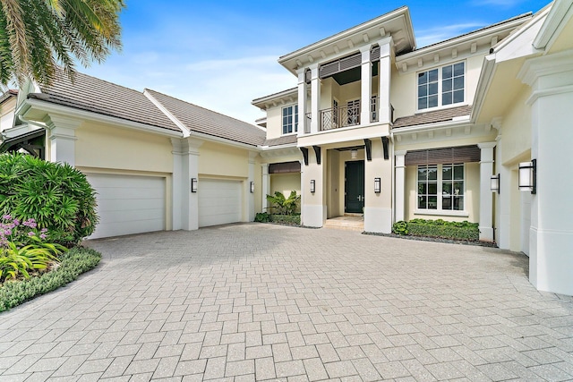13209 Rolling Green Rd, North Palm Beach, FL 33408 - view of front of house with a balcony, stucco siding, decorative driveway, and a garage