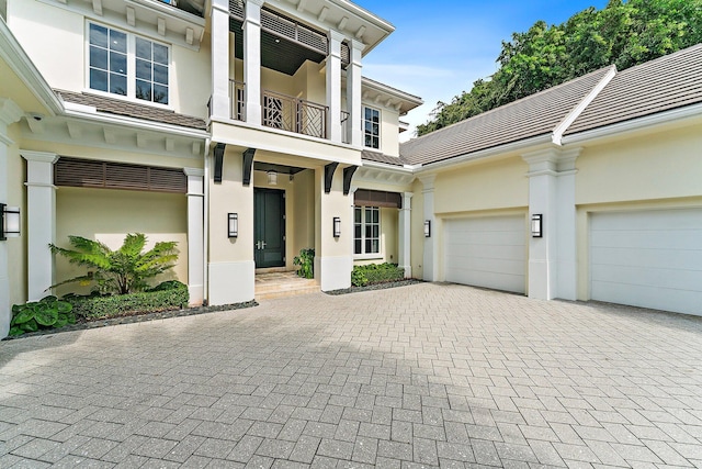 13209 Rolling Green Rd, North Palm Beach, FL 33408 - entrance to property with stucco siding, decorative driveway, a balcony, and a garage