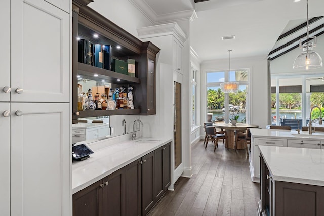 bar with hanging light fixtures, light stone countertops, vaulted ceiling, dark wood-type flooring, and sink