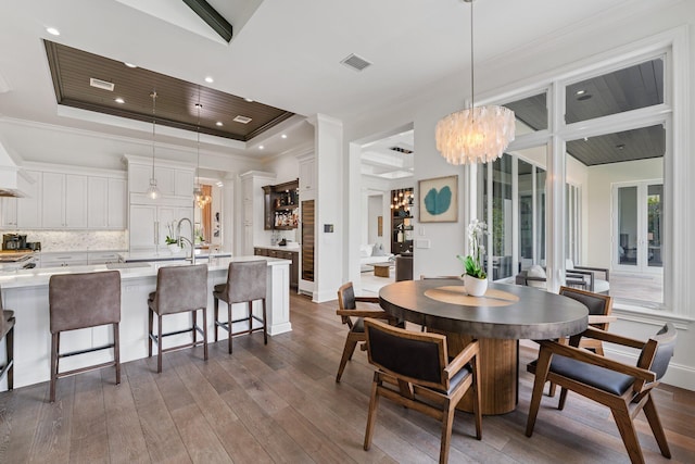 dining room with dark hardwood / wood-style flooring, ornamental molding, a chandelier, and a raised ceiling