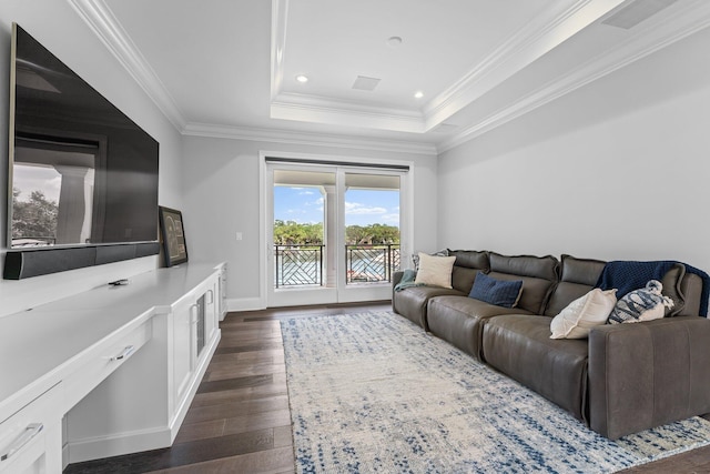 living room with ornamental molding, a tray ceiling, and dark hardwood / wood-style flooring