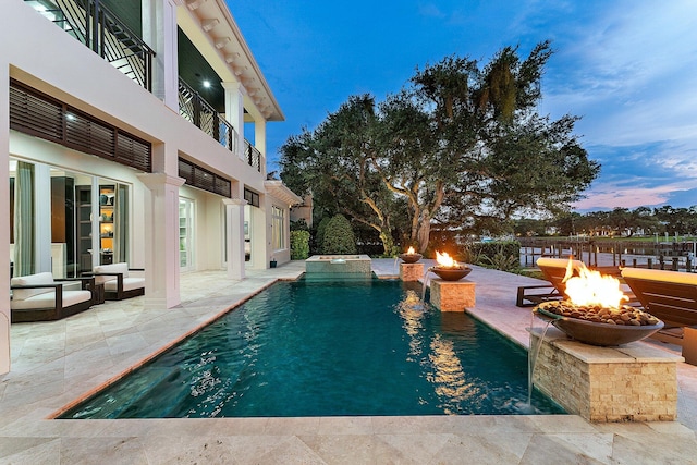 13209 Rolling Green Rd, North Palm Beach, FL 33408 - pool at dusk featuring an outdoor fire pit, a patio, and a pool with connected hot tub